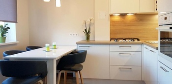 стильная белая угловая кухня с пластиковыми фасадами и столешницей под дерево