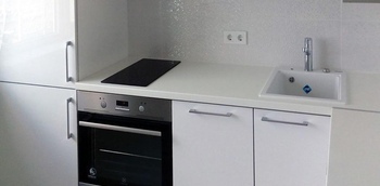 маленькая угловая кухня с белыми матовыми фасадами и белой столешницей на заказ