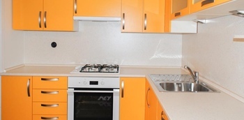 угловая кухня с матовыми фасадами из пластика оранжевого цвета и светлой столешницей на заказ