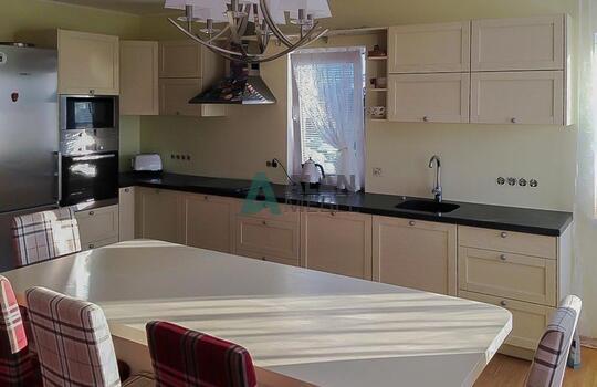 Г-образная кухня молочного цвета с матовыми рамочными фасадами и черной столешницей на заказ 