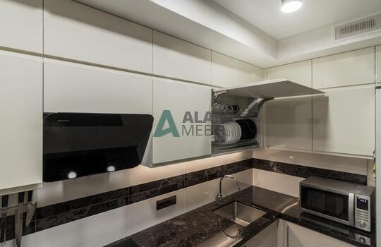 современная п-образная кухня из шпона ясеня бежевого цвета с черной глянцевой столешницей 