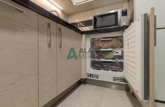 современная п-образная кухня из шпона ясеня бежевого цвета с черной глянцевой столешницей 