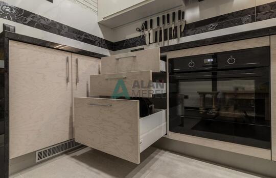 современная п-образная кухня из шпона ясеня бежевого цвета с черной глянцевой столешницей 