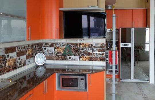 большая Г-образная кухня оранжевого цвета с темной столешницей под заказ по индивидуальным размерам 