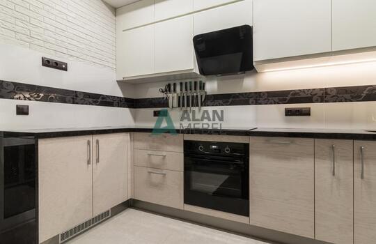 современная п-образная кухня из шпона ясеня бежевого цвета с черной глянцевой столешницей 