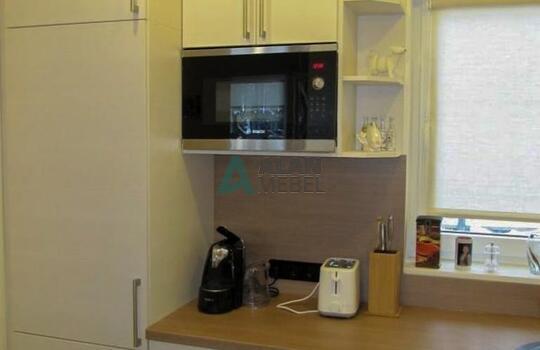 большая Г-образная кухня с матовыми фасадами светлого цвета с мойкой под окно в частный дом 