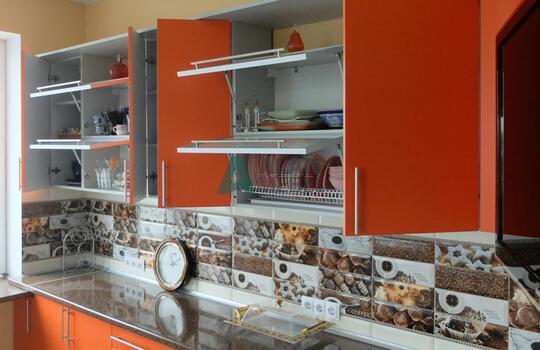 большая Г-образная кухня оранжевого цвета с темной столешницей под заказ по индивидуальным размерам 