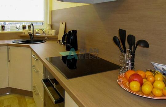 большая Г-образная кухня с матовыми фасадами светлого цвета с мойкой под окно в частный дом 